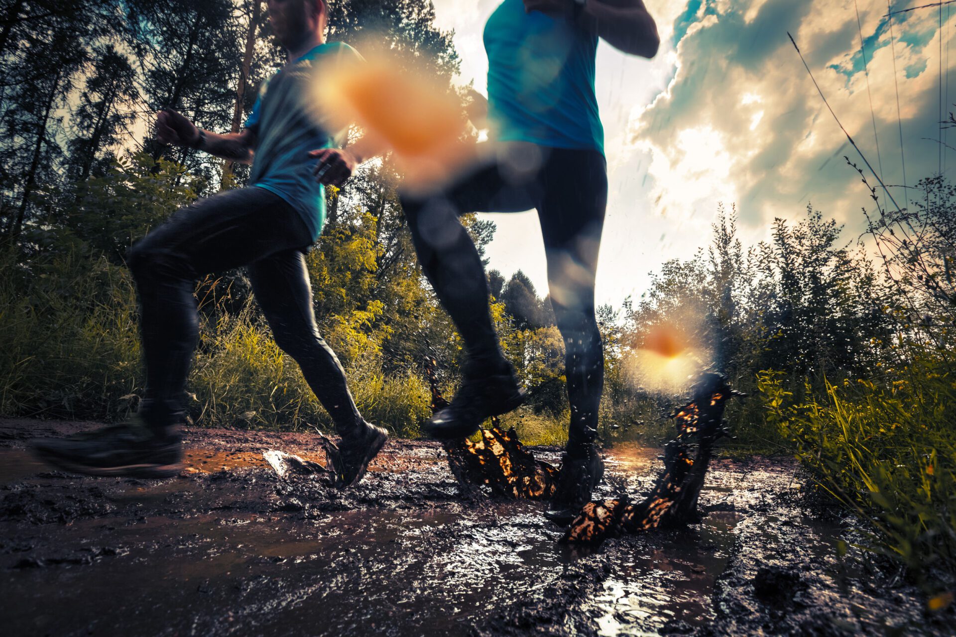 Two trail running athlete moving through the dirty puddle in the rural road